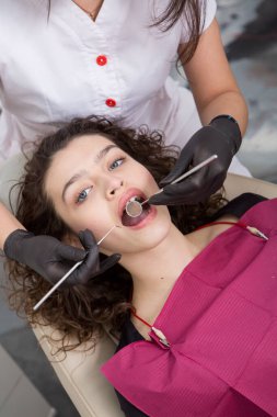 Güzel gülüşü olan genç bir bayan hasta dişçi kliniğinde diş muayenesi yapıyor. Sağlıklı dişler ve ilaçlar, stomatoloji konsepti