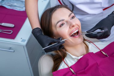 Güzel gülüşü olan genç bir bayan hasta dişçi kliniğinde diş muayenesi yapıyor. Sağlıklı dişler ve ilaçlar, stomatoloji konsepti