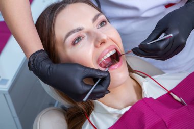 Güzel gülüşü olan genç bir bayan hasta dişçi kliniğinde diş muayenesi yapıyor. Sağlıklı dişler ve ilaçlar, stomatoloji konsepti