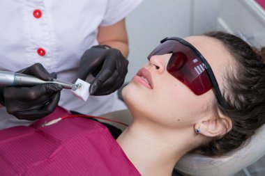 Dişçi, dişçi kliniğinde genç bir kadının dişlerini muayene ediyor. Dişçi konsepti. Diş hekimi ve hasta muayenehanesinde..