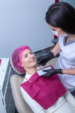 Dişçi, dişçi kliniğinde genç bir kadının dişlerini muayene ediyor. Dişçi konsepti. Diş hekimi ve hasta muayenehanesinde..