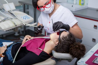 Stomatoloji ve diş bakımı. Diş hekimliği ve oral sağlık. Kadının dişçi kliniğinde diş muayenesi var. Yaklaş genç beyaz kız yüzü..