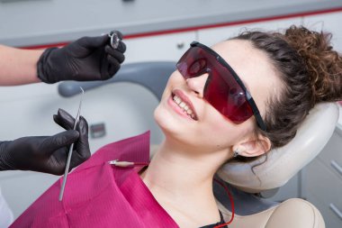 Stomatoloji ve diş bakımı. Diş hekimliği ve oral sağlık. Kadının dişçi kliniğinde diş muayenesi var. Yaklaş genç beyaz kız yüzü..