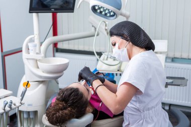 Stomatoloji ve diş bakımı. Diş hekimliği ve oral sağlık. Kadının dişçi kliniğinde diş muayenesi var. Yaklaş genç beyaz kız yüzü..