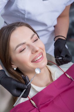 Stomatoloji ve diş bakımı. Diş hekimliği ve oral sağlık. Kadının dişçi kliniğinde diş muayenesi var. Yaklaş genç beyaz kız yüzü..