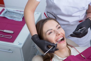 Stomatoloji ve diş bakımı. Diş hekimliği ve oral sağlık. Kadının dişçi kliniğinde diş muayenesi var. Yaklaş genç beyaz kız yüzü..