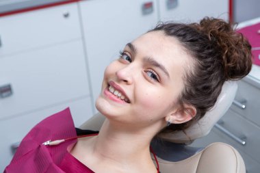Stomatoloji ve diş bakımı. Diş hekimliği ve oral sağlık. Kadının dişçi kliniğinde diş muayenesi var. Yaklaş genç beyaz kız yüzü..