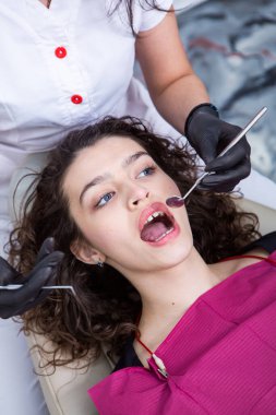 Stomatoloji ve diş bakımı. Diş hekimliği ve oral sağlık. Kadının dişçi kliniğinde diş muayenesi var. Yaklaş genç beyaz kız yüzü..