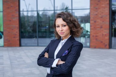 Zarif bir takım elbise giymiş başarılı bir kadın, ofisin önünde poz veriyor. Kadın iş adamı..