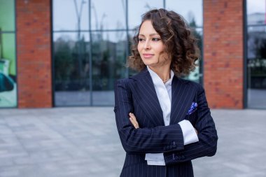 Zarif bir takım elbise giymiş başarılı bir kadın, ofisin önünde poz veriyor. Kadın iş adamı..