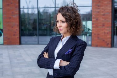 Zarif bir takım elbise giymiş başarılı bir kadın, ofisin önünde poz veriyor. Kadın iş adamı..