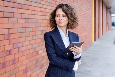 Zarif bir takım elbise giymiş başarılı bir kadın, ofisin önünde poz veriyor. Kadın iş adamı..