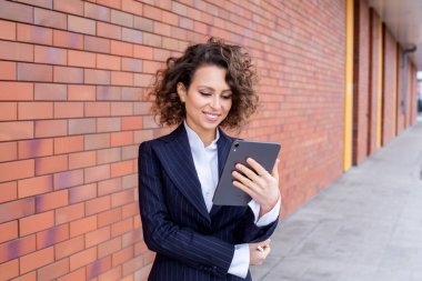 Zarif bir takım elbise giymiş başarılı bir kadın, ofisin önünde poz veriyor. Kadın iş adamı..