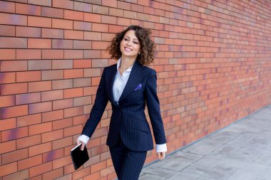 Zarif bir takım elbise giymiş başarılı bir kadın, ofisin önünde poz veriyor. Kadın iş adamı..