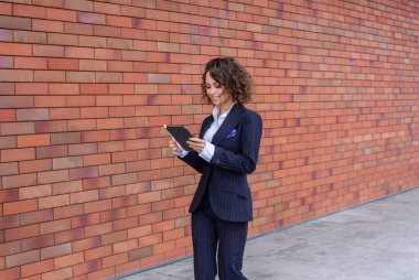 Zarif bir takım elbise giymiş başarılı bir kadın, ofisin önünde poz veriyor. Kadın iş adamı..