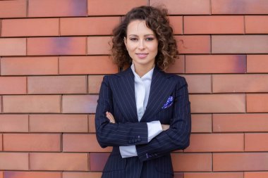 Zarif bir takım elbise giymiş başarılı bir kadın, ofisin önünde poz veriyor. Kadın iş adamı..