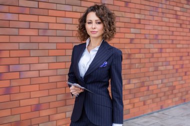 Zarif bir takım elbise giymiş başarılı bir kadın, ofisin önünde poz veriyor. Kadın iş adamı..