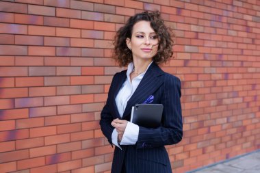 Zarif bir takım elbise giymiş başarılı bir kadın, ofisin önünde poz veriyor. Kadın iş adamı..