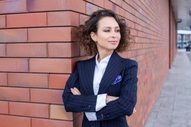 Zarif bir takım elbise giymiş başarılı bir kadın, ofisin önünde poz veriyor. Kadın iş adamı..