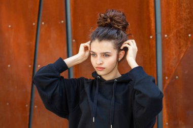 Beyaz esmer, kıvırcık saçlı kız şehirde sokakta poz veriyor..