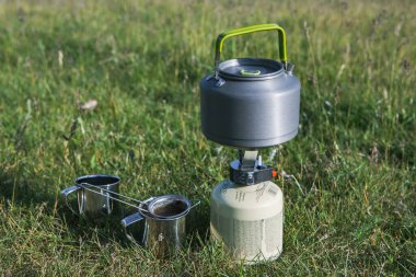 Yeşil doğadaki bir gaz ocağında kaynayan bir çaydanlığın yakın çekimi. Yürürken sıcak bir şeyler içiyorum. Turizm kavramı