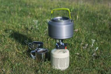 Yeşil doğadaki bir gaz ocağında kaynayan bir çaydanlığın yakın çekimi. Yürürken sıcak bir şeyler içiyorum. Turizm kavramı