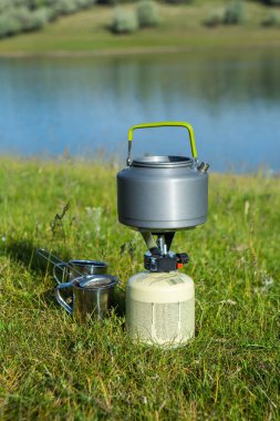 Yeşil doğadaki bir gaz ocağında kaynayan bir çaydanlığın yakın çekimi. Yürürken sıcak bir şeyler içiyorum. Turizm kavramı