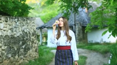 Kırsalda Rumen geleneksel bluzu giyen genç bir kızın videosu. Romanya geleneğinin özgün ulusal kostümü.