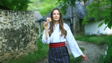 Kırsalda Rumen geleneksel bluzu giyen genç bir kızın videosu. Romanya geleneğinin özgün ulusal kostümü.