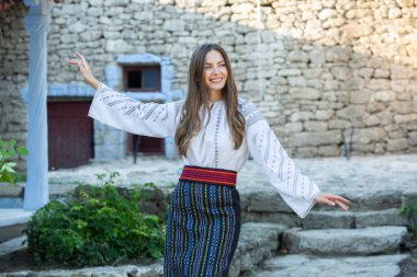 Kırsalda Rumen geleneksel bluzu giyen genç bir kızın videosu. Romanya geleneğinin özgün ulusal kostümü.