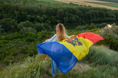 Moldova Cumhuriyeti bayrağını doğadaki güzel bir tepede tutan güzel bayan..
