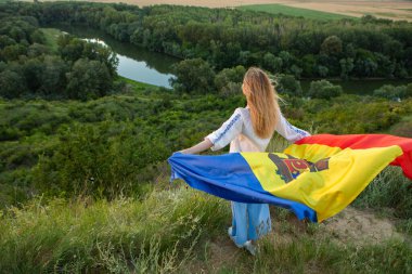 Moldova Cumhuriyeti bayrağını doğadaki güzel bir tepede tutan güzel bayan..