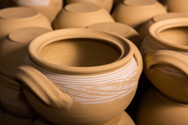 Çömlek atölyesindeki ahşap raflarda kuruyan taze kilden kupalar, çömlekler ve kaseler. El yapımı seramik imalatı. Atölyedeki farklı çömlekler. 