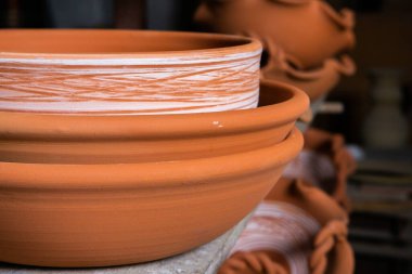 Çömlek atölyesindeki ahşap raflarda kuruyan taze kilden kupalar, çömlekler ve kaseler. El yapımı seramik imalatı. Atölyedeki farklı çömlekler. 