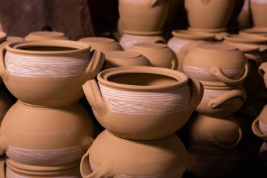 Çömlek atölyesindeki ahşap raflarda kuruyan taze kilden kupalar, çömlekler ve kaseler. El yapımı seramik imalatı. Atölyedeki farklı çömlekler. 