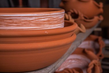 Çömlek atölyesindeki ahşap raflarda kuruyan taze kilden kupalar, çömlekler ve kaseler. El yapımı seramik imalatı. Atölyedeki farklı çömlekler. 