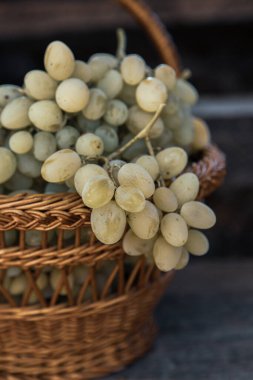 Tahta bir arka planda sepette bir demet beyaz üzüm..