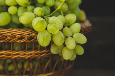 Tahta bir arka planda sepette bir demet beyaz üzüm..