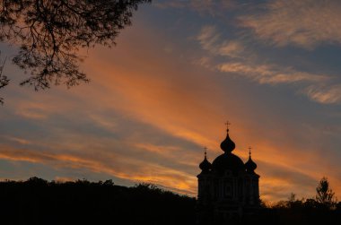 Batan güneşin arka planında bir Ortodoks kilisesinin silueti.