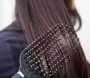 Güzellik salonunda uzun ve güzel esmer saçlı Avrupalı bir kızın fotoğrafı. Parlak ve sağlıklı saçlar..