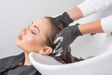 Uzun kahverengi saçlı bir güzellik salonunda çalışan profesyonel bir kuaför. Moda Kadını Kuaför Salonunda Kuaför Muamelesi