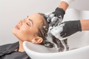 Uzun kahverengi saçlı bir güzellik salonunda çalışan profesyonel bir kuaför. Moda Kadını Kuaför Salonunda Kuaför Muamelesi