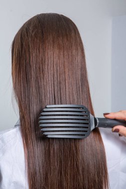 Uzun kahverengi saçlı bir güzellik salonunda çalışan profesyonel bir kuaför. Moda Kadını Kuaför Salonunda Kuaför Muamelesi