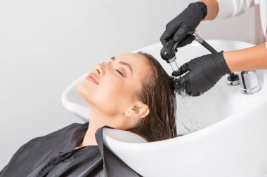 Lüks bir salonda makyajdan zevk alan büyüleyici kadın. Moda Kadını Kuaför Salonunda Kuaför Muamelesi.