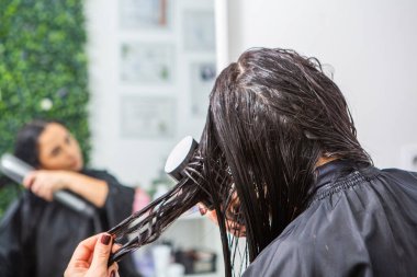 Güzellik salonunda uzun kahverengi saçlı güzel bir genç kadın. Saçını kurutan kız..