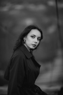 Doğada mavi trençkotlu güzel esmer Avrupalı kız. Güzel yüzlü ve dudaklı genç bayan.