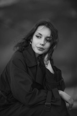 Doğada mavi trençkotlu güzel esmer Avrupalı kız. Güzel yüzlü ve dudaklı genç bayan.