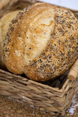 Beyaz zemin üzerinde susamlı ve ayçiçeği tohumlu tam bir buğday ekmeği.