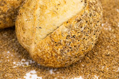 Beyaz zemin üzerinde susamlı ve ayçiçeği tohumlu tam bir buğday ekmeği.