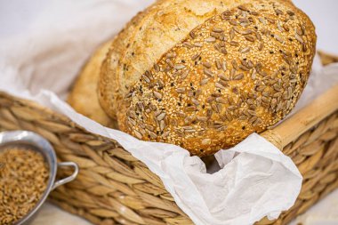 Beyaz zemin üzerinde susamlı ve ayçiçeği tohumlu tam bir buğday ekmeği.